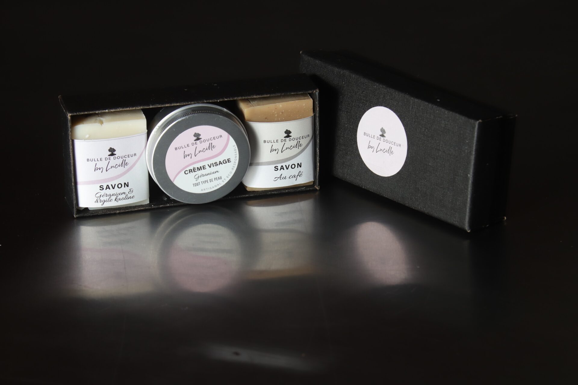 Coffret soin Bulle de Douceur by Lucille comprenant deux savons artisanaux (géranium & argile kaolin et café) et une crème visage au géranium, présenté dans un élégant coffret noir